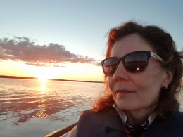 Photo of woman with sunglasses in front of a sun set on a lake