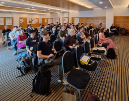 Photo showing people sitting on chairs arranged in rows in a meeting room