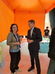Woman standing next to man dressed in dark suit under an orange tent cover